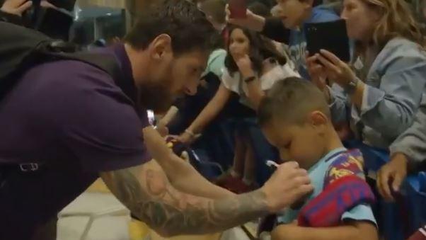Leo Messi firmando la camiseta de otro de los niños presentes. 