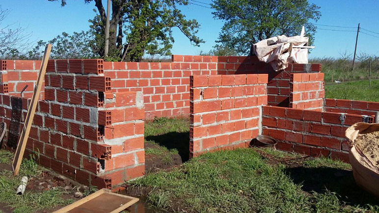 La familia está construyendo una vivienda de material muy cerca.