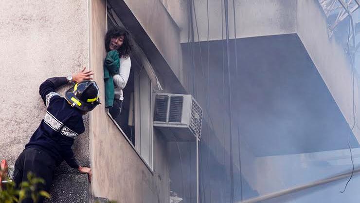 Una ventana, una mujer y un héroe vestido de bombero 