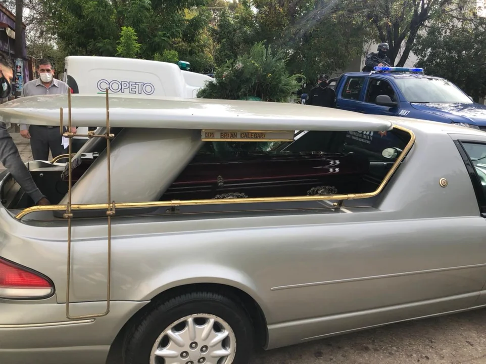 El coche fúnebre y, al fondo, un móvil policial para vigilar la seguridad del sepelio.