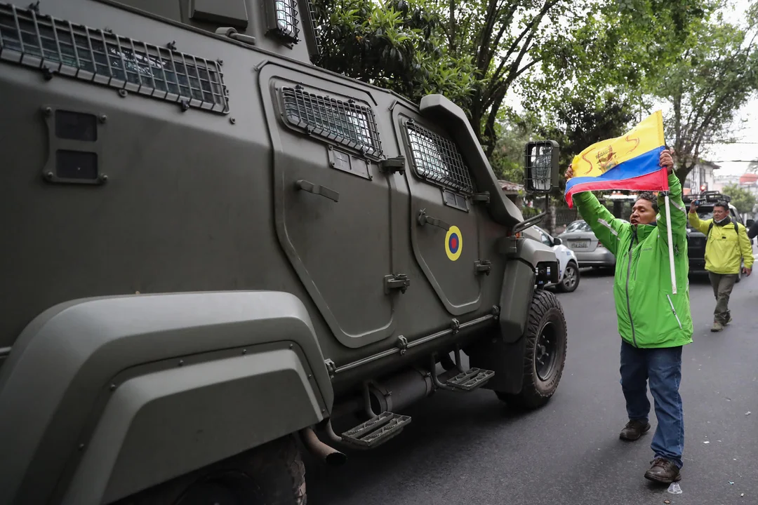  Un hombre exhibe una bandera mientras pasa un vehículo blindado donde es trasladado el exvicepresidente ecuatoriano Jorge Glas, este sábado en Quito. (Fotografía: EFE/ José Jácome)